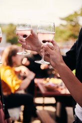 Cropped Hände von Freunden halten Weingläser während geselligem Beisammensein auf der Terrasse - MASF11584