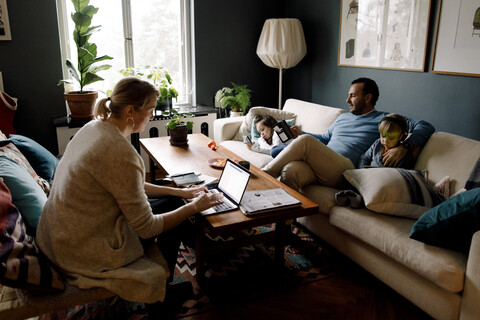 Familie nutzt verschiedene Technologien im heimischen Wohnzimmer, lizenzfreies Stockfoto