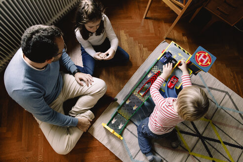 Hohe Winkelansicht von Vater und Töchtern mit Spielzeugautos zu Hause - MASF11597