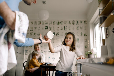 Lächelnde Tochter gibt Vater in der Küche zu Hause eine Tasse, lizenzfreies Stockfoto