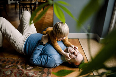 Verspielte Tochter kneift fröhlichen Vater die Wangen auf dem Boden zu Hause - MASF11612