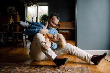 Voller Länge von glücklichen spielerischen Vater trägt Tochter, während auf Hartholzboden zu Hause sitzen - MASF11613