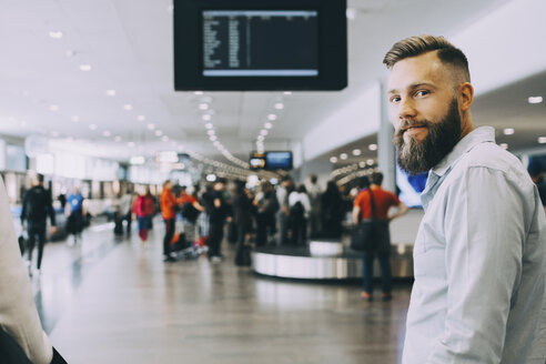 Porträt eines lächelnden Geschäftsmanns, der mit einer Geschäftsfrau am Flughafen steht - MASF11630