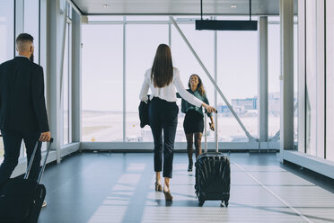 Smiling businesswoman walking towards female colleague in corridor at airport - MASF11642