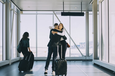 Businesswoman walking by colleagues greeting in corridor at airport - MASF11644