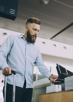 Niedriger Blickwinkel von Geschäftsmann Scannen Ticket auf Smartphone am Flughafen Check-in Schalter - MASF11654