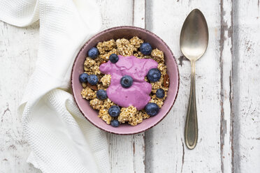 Granola with blueberries and blueberry yoghurt in bowl on white wood - LVF07883