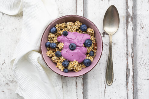 Granola mit Blaubeeren und Blaubeerjoghurt in Schale auf weißem Holz - LVF07883