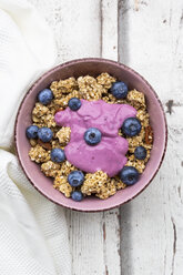 Granola mit Blaubeeren und Blaubeerjoghurt in Schale auf weißem Holz - LVF07885