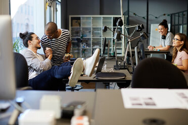 Lächelnde männliche Unternehmer, die sich am Schreibtisch in einem kreativen Büro begrüßen - MASF11720