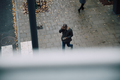 Hohe Winkel Ansicht der Geschäftsmann mit Smartphone beim Gehen auf der Straße Stadt, lizenzfreies Stockfoto