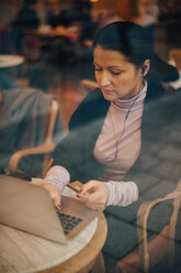 Hohe Winkel Ansicht der Geschäftsfrau tun Online-Shopping über Laptop beim Sitzen im Café durch das Fenster gesehen - MASF11758