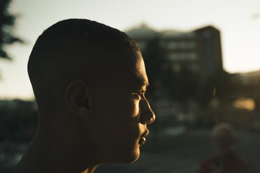 Seitenansicht eines nachdenklichen Teenagers, der bei Sonnenuntergang in der Stadt wegschaut - MASF11770