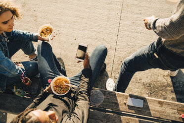 Hohe Winkel Ansicht der Teenager-Junge mit Smartphone beim Essen Mahlzeit mit Freunden auf der Straße in der Stadt - MASF11794