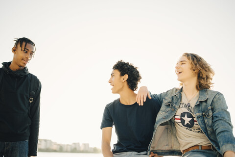 Glückliche männliche Freunde verbringen Freizeit gegen klaren Himmel in der Stadt, lizenzfreies Stockfoto