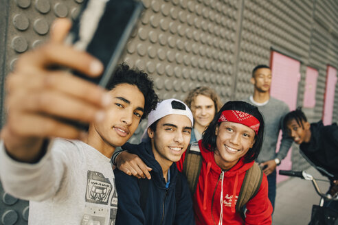 Glückliche männliche Freunde nehmen Selfie mit Smartphone in der Stadt - MASF11824