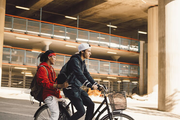 Seitenansicht eines jungen Mannes, der mit einem Freund in der Stadt Fahrrad fährt - MASF11826