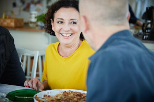Fröhliche reife Frau im Gespräch mit einem männlichen Freund beim Mittagessen zu Hause - MASF11831