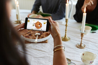 Ältere Frau benutzt ihr Smartphone beim Mittagessen mit Freunden zu Hause - MASF11832