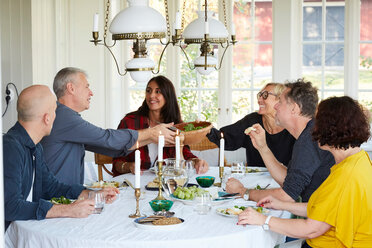 Glückliche reife Freunde beim gemeinsamen Mittagessen im Esszimmer zu Hause während eines gesellschaftlichen Treffens - MASF11833