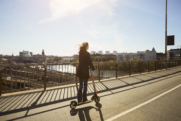 In voller Länge der weiblichen Pendler Reiten elektrische Push-Roller auf Brücke in der Stadt gegen den Himmel - MASF11860