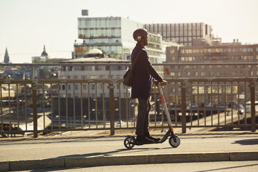 Full length of young man riding electric push scooter on bridge in city - MASF11861