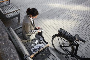 High angle view of woman surfing net through smart phone while sitting on bench in city - MASF11871