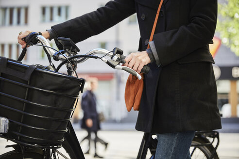 Mittelteil eines weiblichen Pendlers, der mit einem Elektrofahrrad in der Stadt unterwegs ist - MASF11873