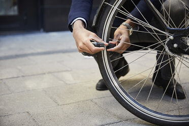 Niedriger Ausschnitt eines männlichen Pendlers, der sein Elektrofahrrad gegen ein Gebäude in der Stadt sperrt - MASF11877