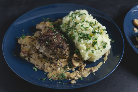 Frikadelle mit Apfel-Zwiebel-Speck-Sahnesoße und Kartoffelpüree, mit Petersilie, lizenzfreies Stockfoto