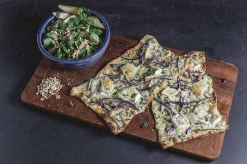 Flammkuchen mit Camembert und Thymian-Creme fraiche und roter Zwiebel auf Schneidebrett, Feldsalat mit Birne in Schale - STBF00259