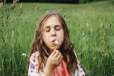 Portrait of girl blowing blowball on a meadow - ANHF00099