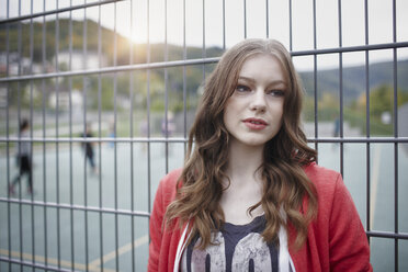 Portrait of teenage girl at a fence at a sports field - RORF01824