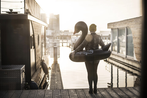 Geschäftsfrau mit schwimmendem Schwan, die auf einem Hausboot steht und in die Ferne schaut, lizenzfreies Stockfoto