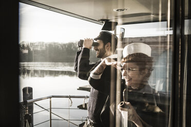 Kollegen arbeiten auf einem Hausboot und beobachten die Umgebung mit einem Fernglas - MJRF00096