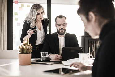 Geschäftsleute arbeiten zusammen im Büro, Geschäftsfrau beobachtet Kollegin, schaut über die Schulter - MJRF00108