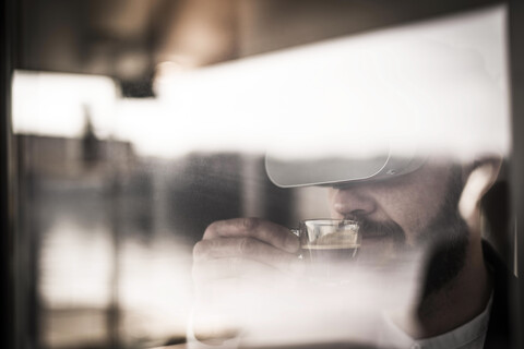 Geschäftsmann mit VR-Brille genießt seinen Kaffee, lizenzfreies Stockfoto