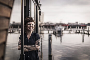 Woman leaning in window of a houseboat, taking a break - MJRF00145