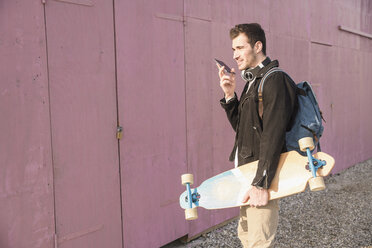 Young man with skatebaord and cell phone on the move - UUF16762