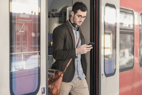 Junger Mann benutzt Mobiltelefon im Nahverkehrszug - UUF16826