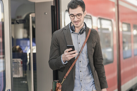 Young man using cell phone at commuter train stock photo