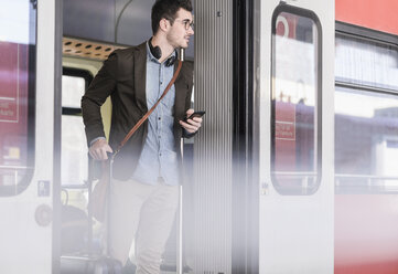 Junger Mann mit Mobiltelefon im Nahverkehrszug - UUF16830