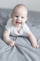 Portrait of laughing baby boy lying on bed - STBF00272