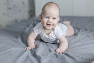 Porträt eines lachenden kleinen Jungen auf dem Bett liegend - STBF00273