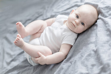 Portrait of baby boy lying on bed - STBF00274