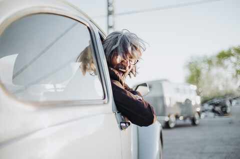 Senior man leaning out of window of vintage car screaming stock photo