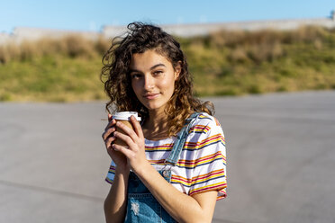 Young woman drinking coffee from a disposable cup - AFVF02611