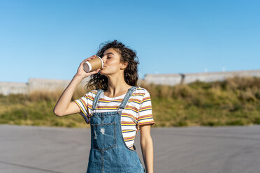 Young woman drinking coffee from a disposable cup - AFVF02612