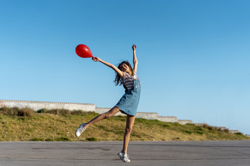 Junge Frau hält roten Ballon und tanzt - AFVF02619
