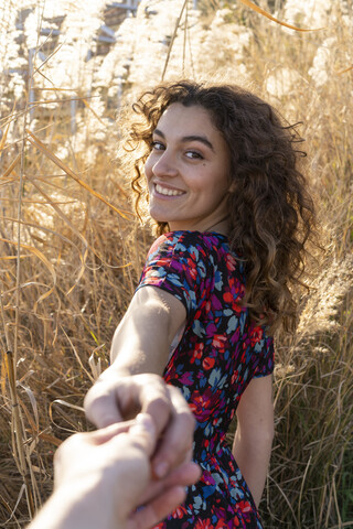 Junge Frau steht auf einer Wiese und hält die Hand eines jungen Mannes, lizenzfreies Stockfoto